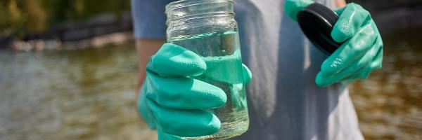 Photo by the University of Vermont Photo of a person holding a jar of lake water